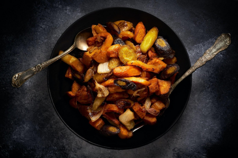 salmon and roasted vegetables on a black plate